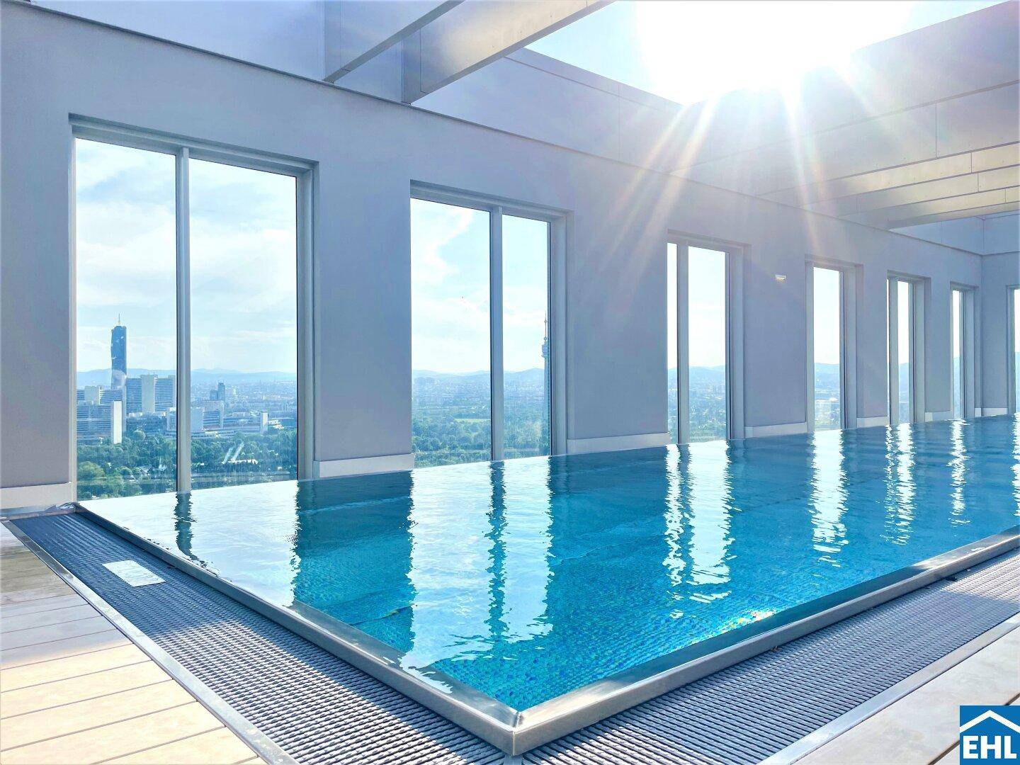 Helles Hallenbad mit Infinity-Pool und Panoramablick auf die Stadt.