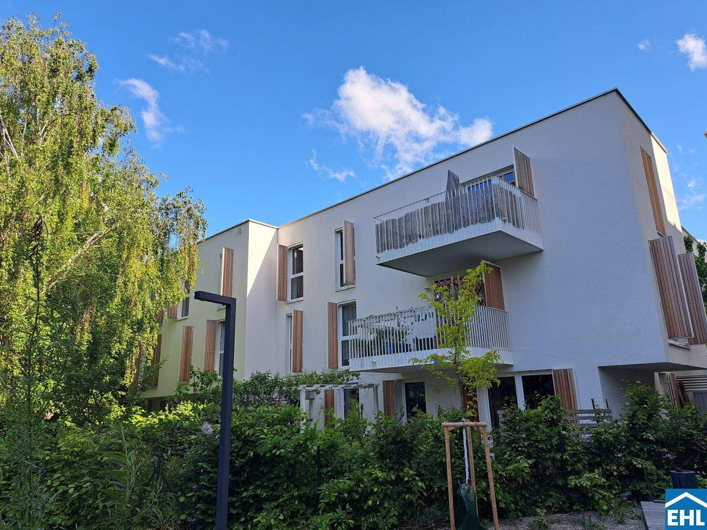 Moderne Wohnanlage mit hellen Fassaden und Balkonen, umgeben von üppigem Grün.