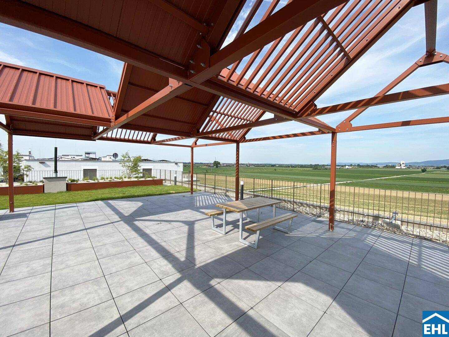 Großzügige Dachterrasse mit Pergola, Sitzgelegenheiten und weitem Blick über die grüne Landschaft.