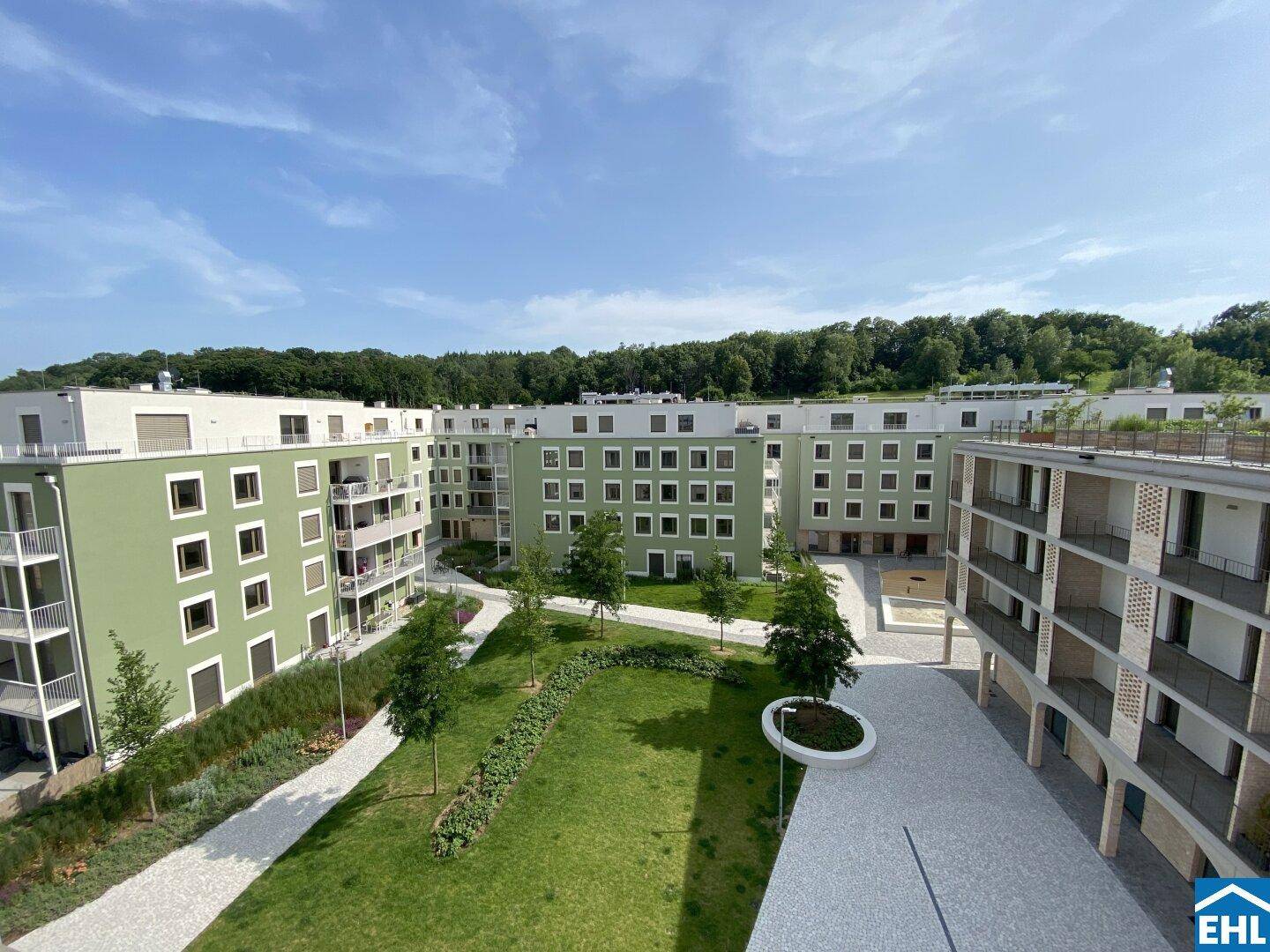 Überblick über eine weitläufige, moderne Wohnanlage mit begrüntem Innenhof und umliegenden Gebäuden.