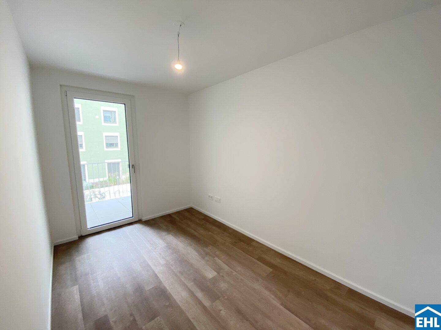 Helles Zimmer mit Laminatboden und direktem Zugang zu einem Außenbereich, ideal als Schlafzimmer.