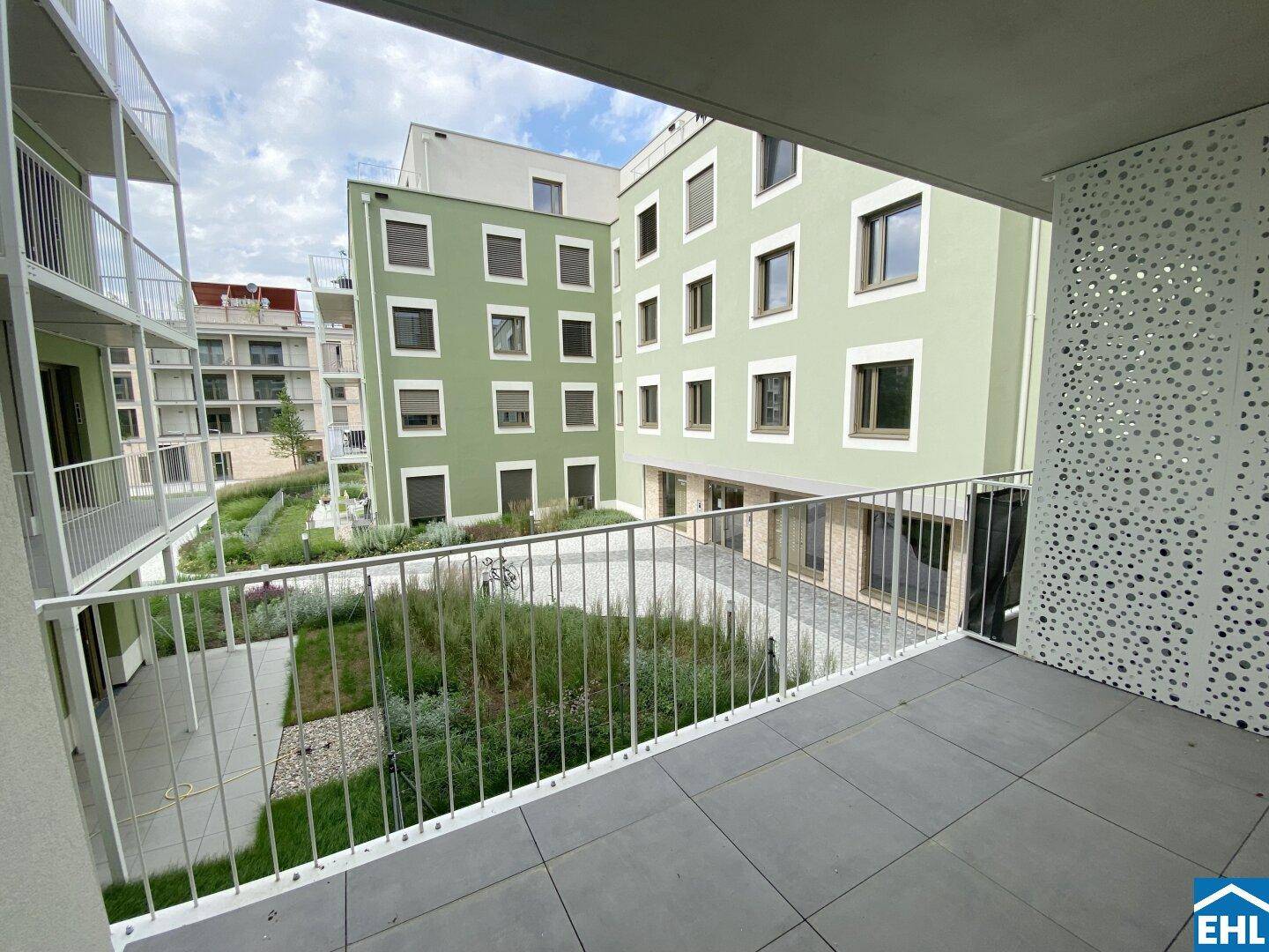 Geräumiger Balkon mit Blick auf den begrünten Innenhof und die moderne Wohnanlage.