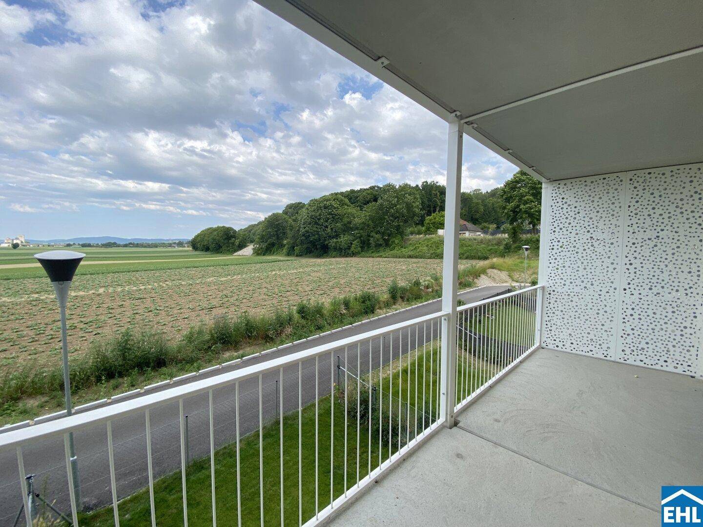 Geräumiger Balkon mit weitem Blick über grüne Felder und die umliegende Landschaft.