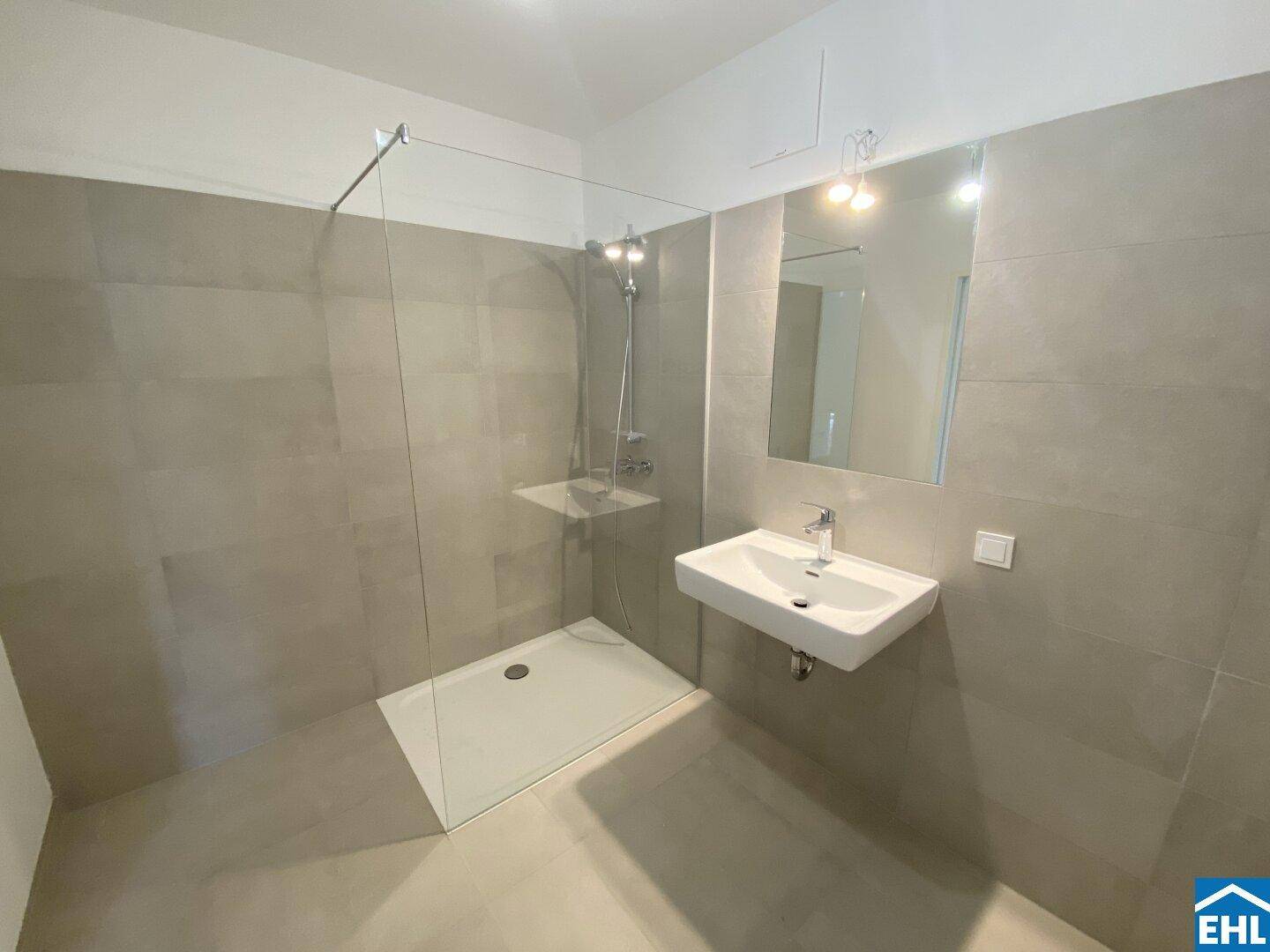 Modernes Badezimmer mit begehbarer Dusche, Wand-WC und großformatigen Fliesen.