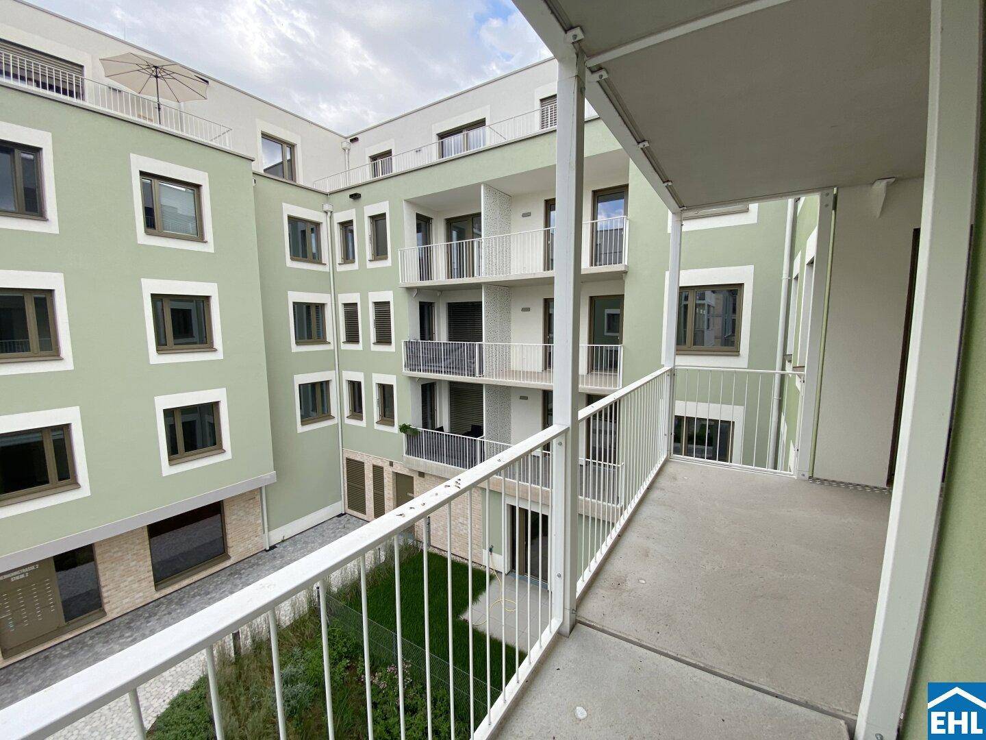 Geräumiger Balkon mit Metallgeländer und weitem Blick über den Innenhof.