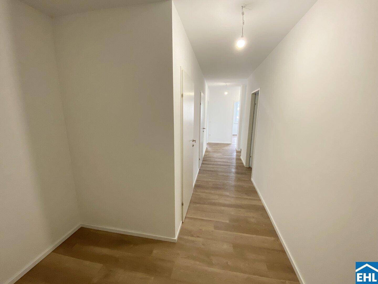 Heller Flur mit Laminatboden und weißen Türen, der zu den verschiedenen Räumen führt.