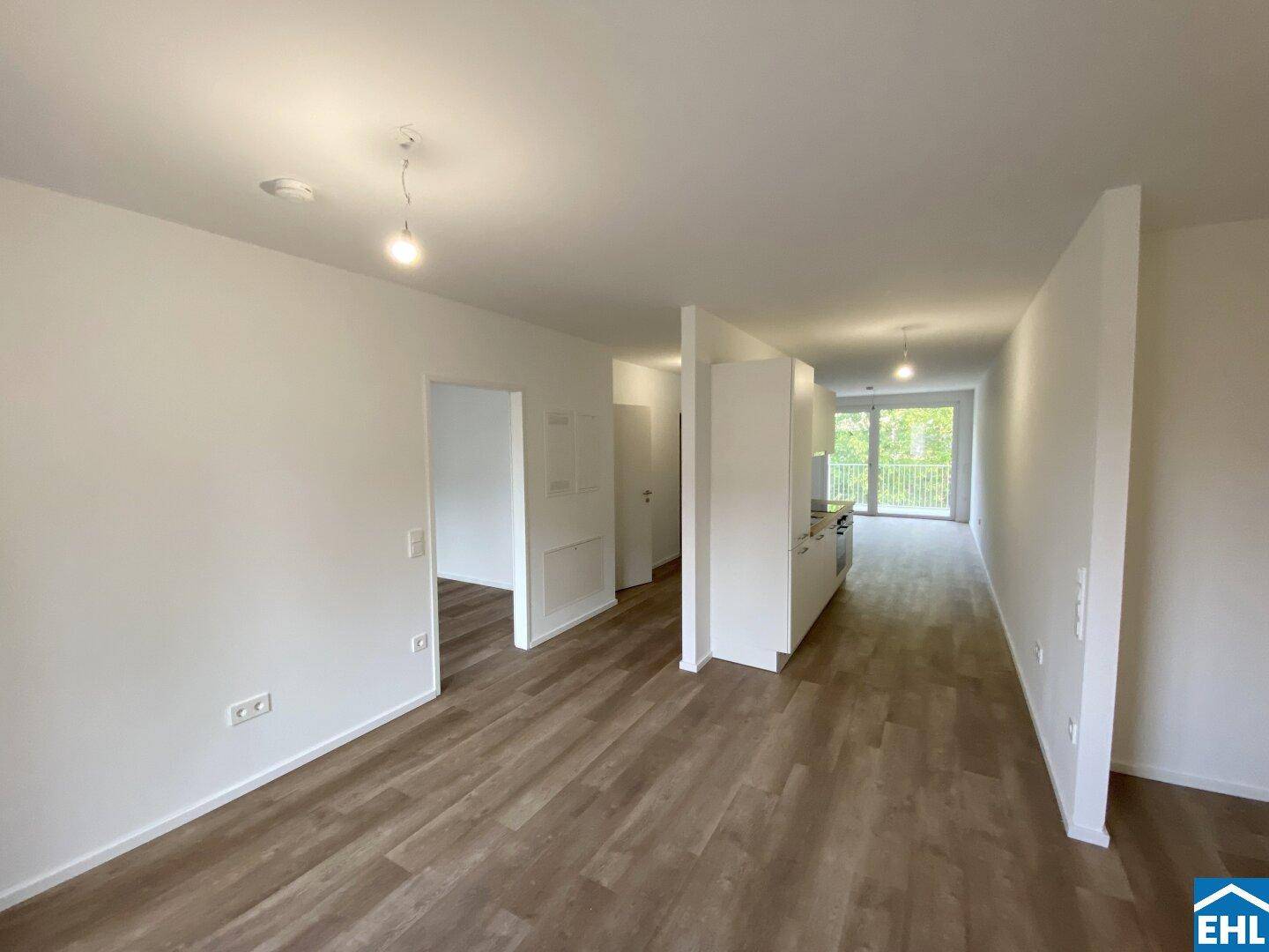 Helles, offenes Wohnzimmer mit modernem Vinylboden und Zugang zu einem Balkon.