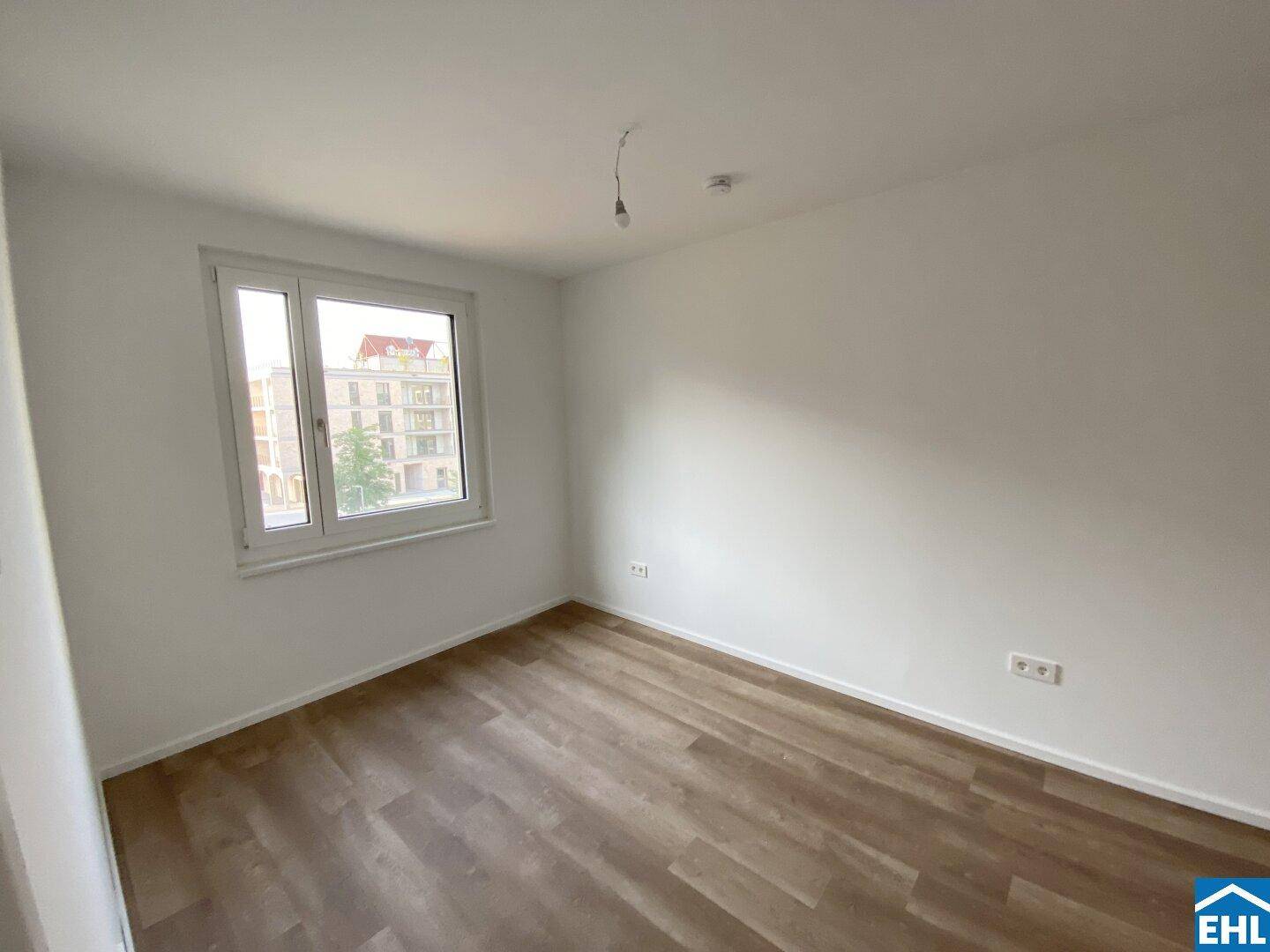 Helles Schlafzimmer mit großem Fenster, modernem Vinylboden und Blick auf die Umgebung.