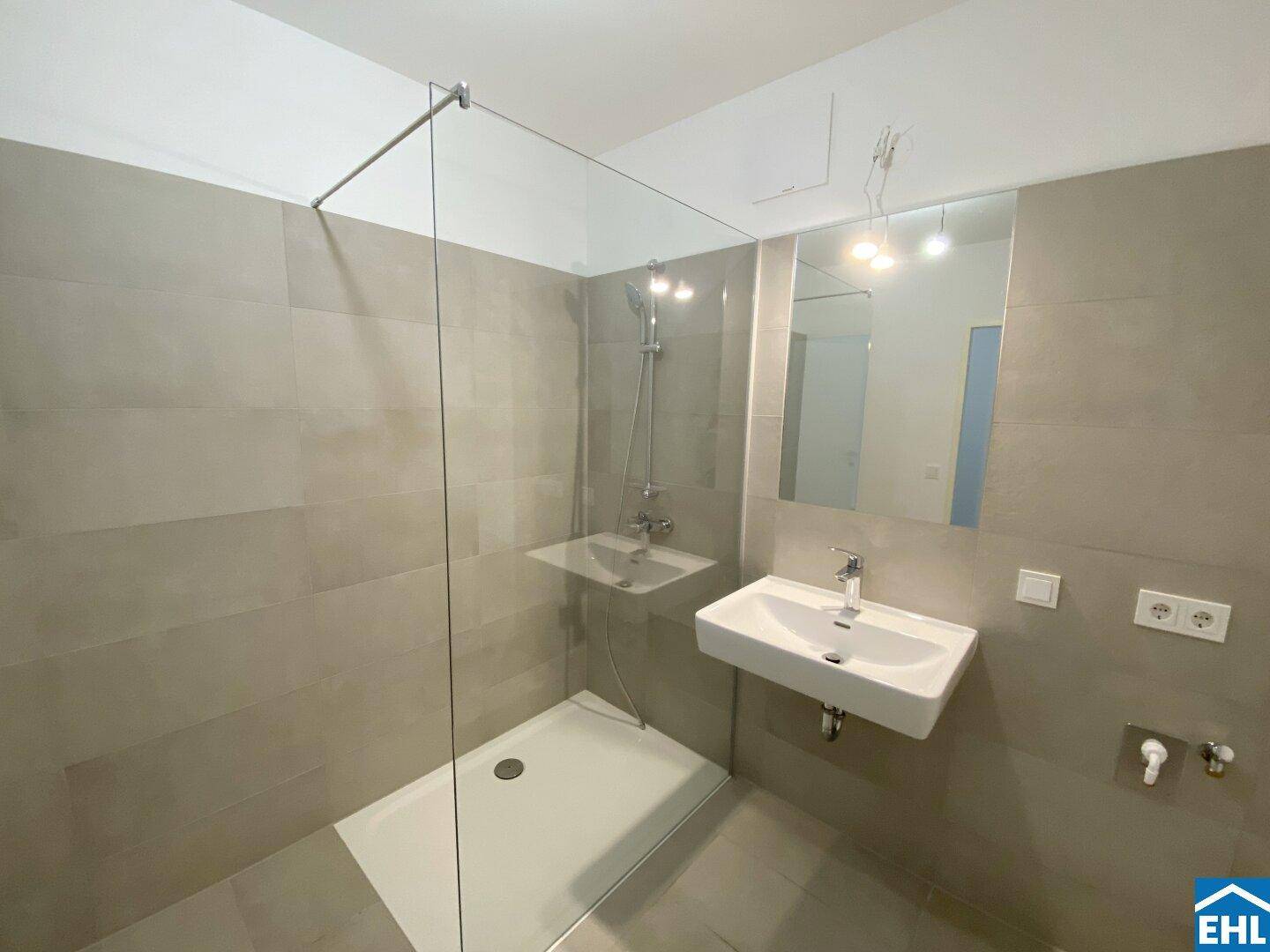 Modernes Badezimmer mit begehbarer Dusche, großformatigen Fliesen und Einzelwaschbecken.