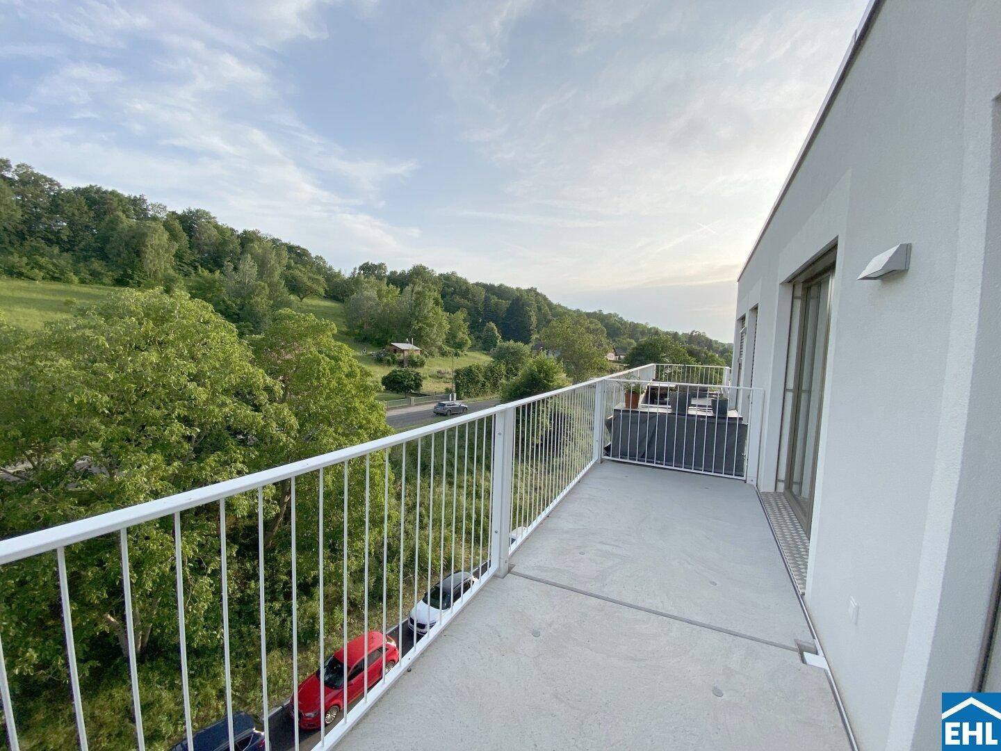 Geräumiger Balkon mit weitem Blick über die grüne Umgebung und die Straße.