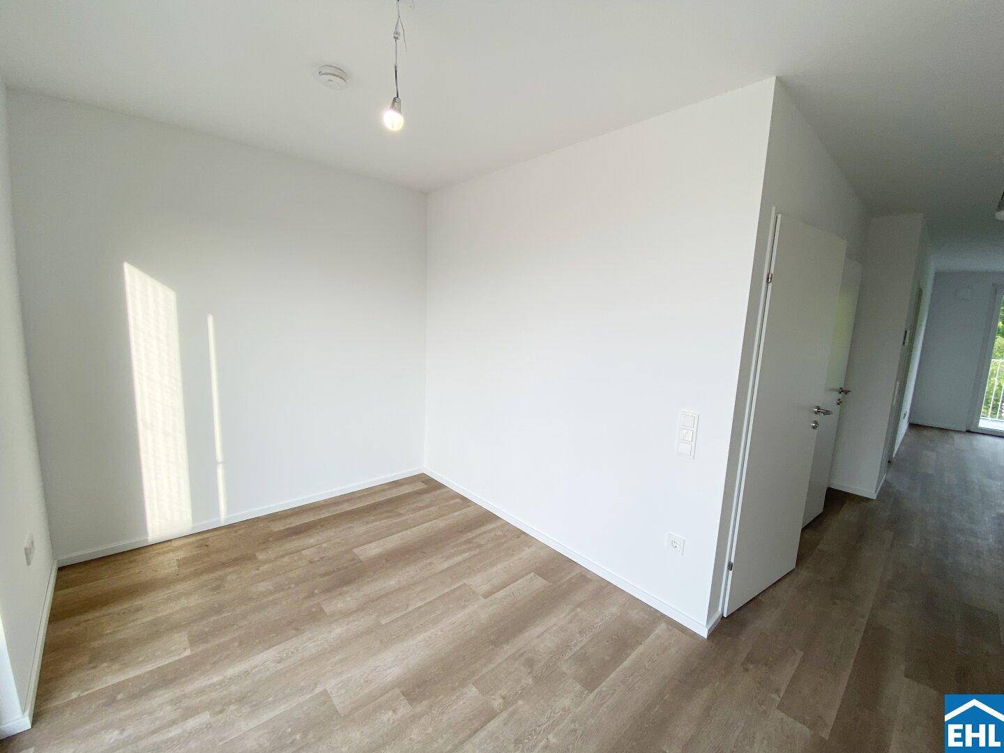 Leeres Zimmer mit hellem Laminatboden und viel Tageslicht, ideal als Schlaf- oder Arbeitszimmer.