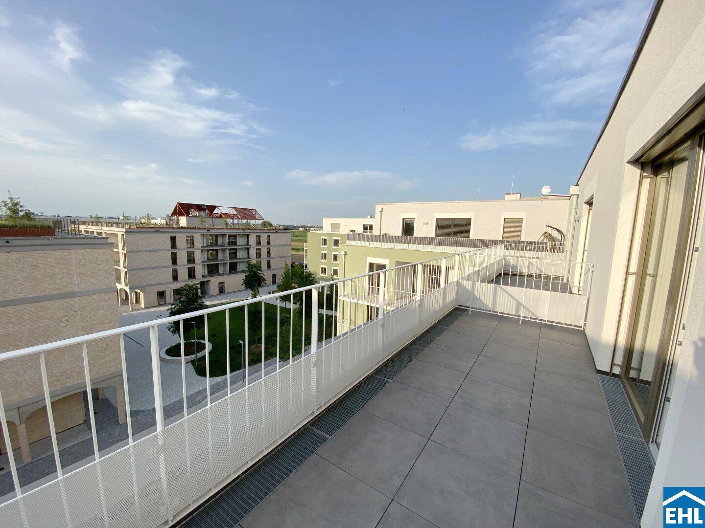 Moderner Balkon mit Blick auf den Innenhof und die umliegenden Gebäude der Wohnanlage.