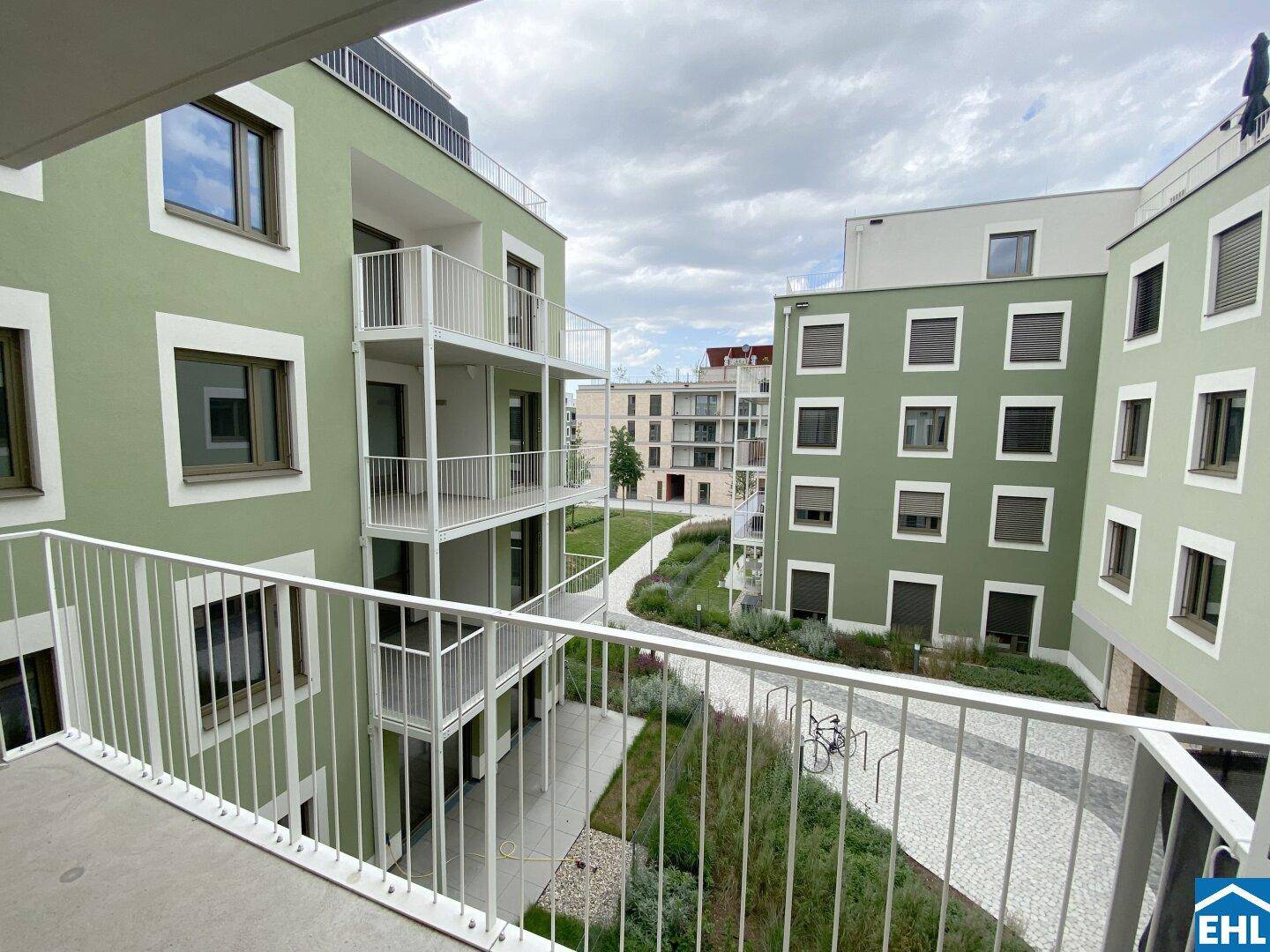 Blick vom Balkon auf eine moderne Wohnanlage mit begrünten Fassaden und gepflegten Außenbereichen.