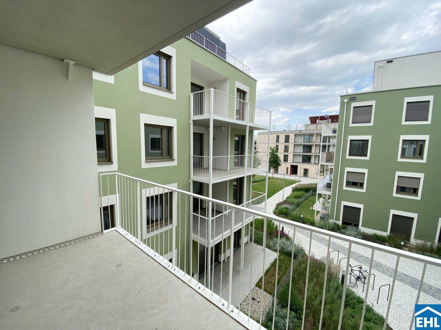 Geräumiger Balkon mit Blick auf die moderne Architektur und die grüne Gestaltung der Wohnanlage.