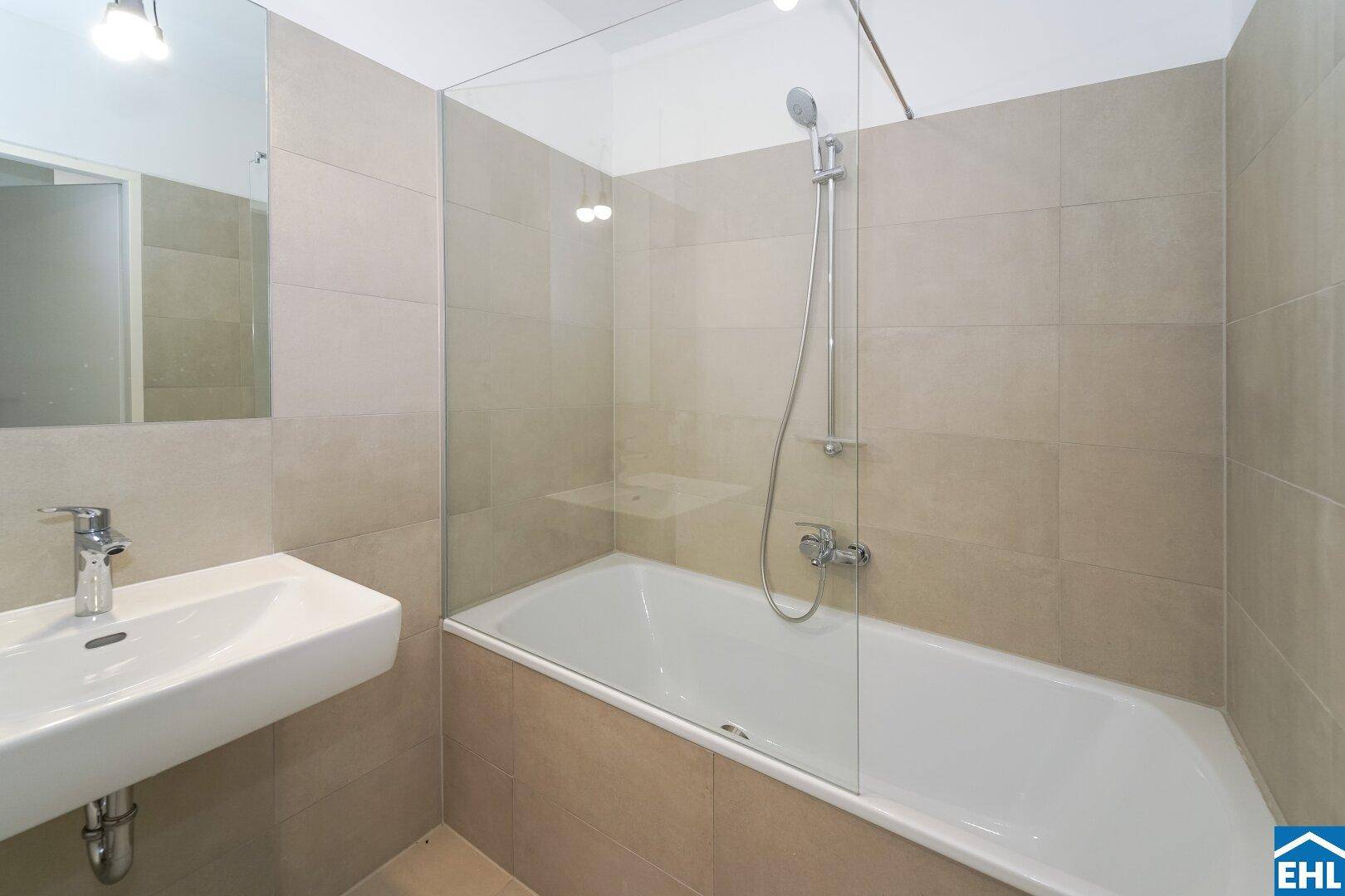 Modernes Badezimmer mit Badewanne, Duschabtrennung aus Glas und hellem Fliesenboden.