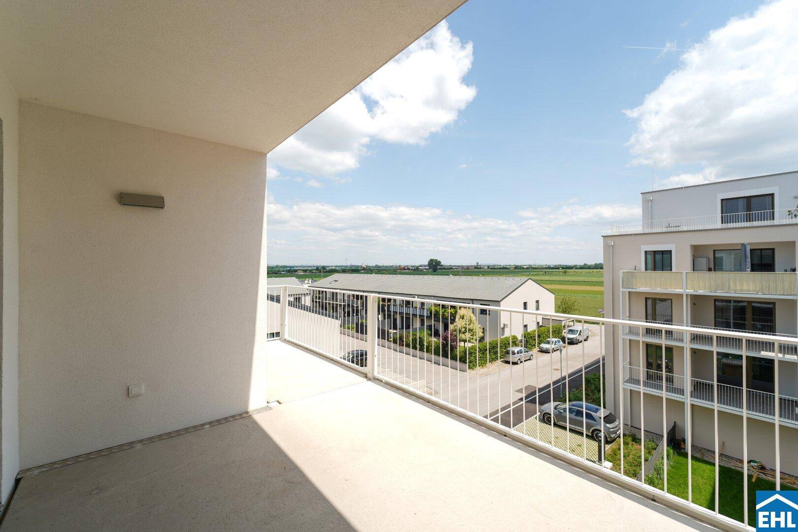 Geräumiger Balkon mit weitem Blick über die Landschaft und angrenzende Gebäude.