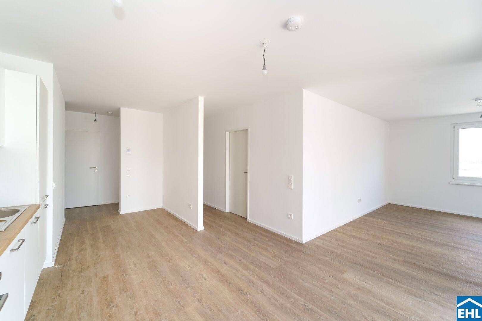 Geräumiger, heller Wohnbereich mit Laminatboden und Zugang zu weiteren Zimmern der Wohnung.