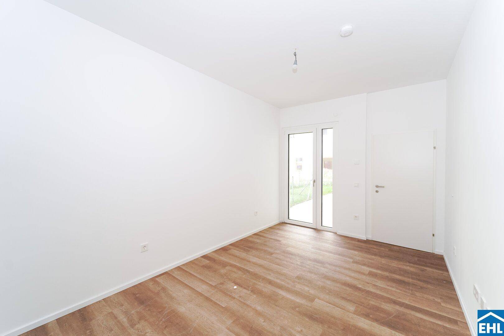 Lichtdurchfluteter Raum mit Vinylboden und Zugang zu einem Außenbereich, ideal als Wohn- oder Schlafzimmer.