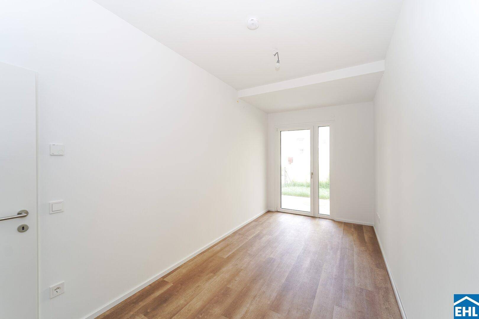 Helles Zimmer mit Vinylboden und Zugang zum Außenbereich, vielseitig nutzbar als Schlaf- oder Arbeitszimmer.
