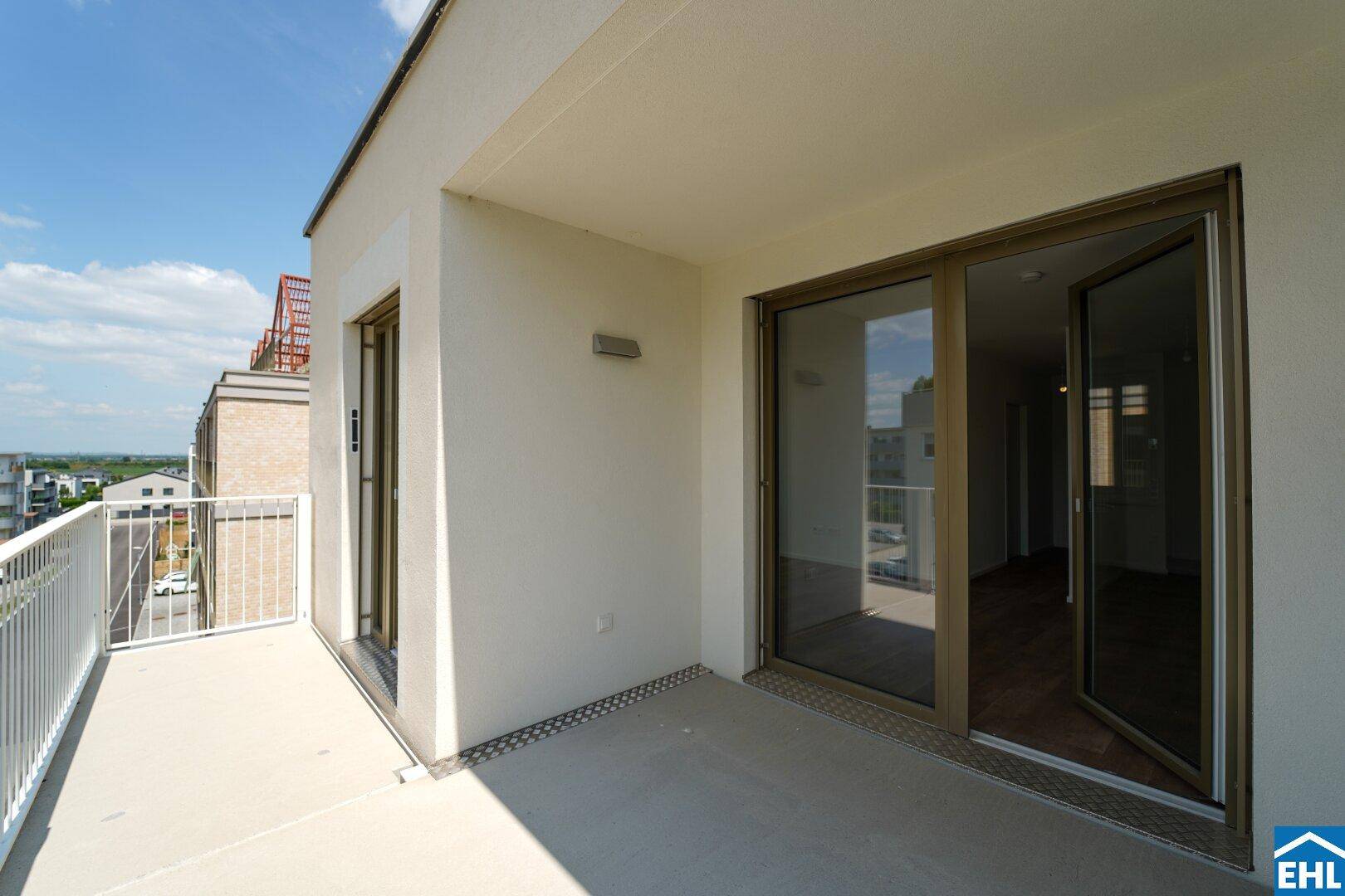 Geräumiger Balkon mit weißem Geländer und Schiebetüren, bietet einen weiten Blick.