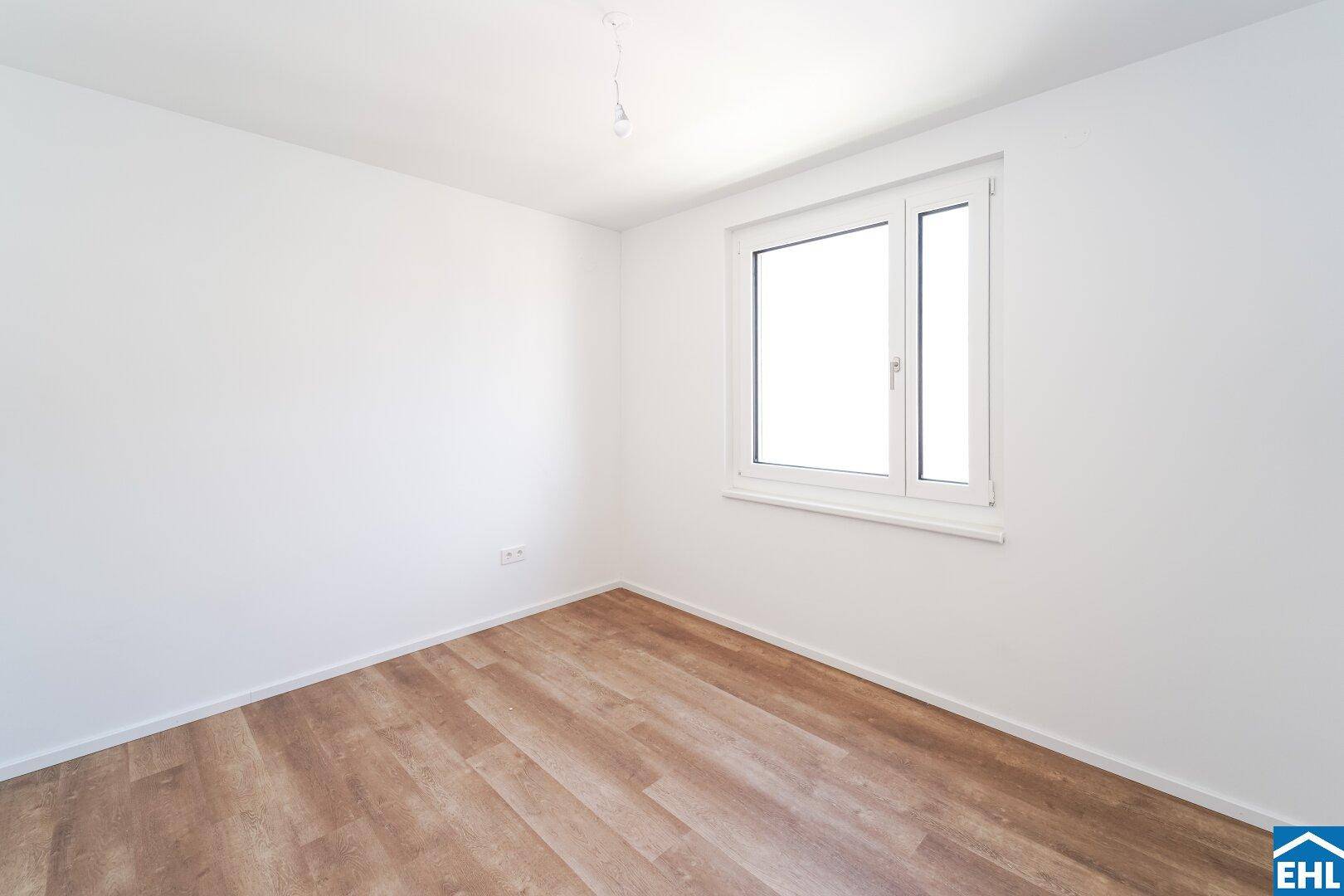 Helles Schlafzimmer mit großem Fenster und neuem Laminatboden, ideal für individuelle Gestaltung.