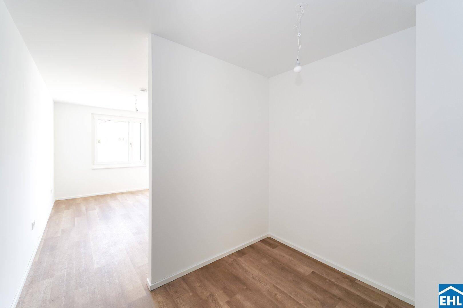 Heller Raum mit Laminatboden und weiß gestrichenen Wänden, ideal als Büro oder Gästezimmer.