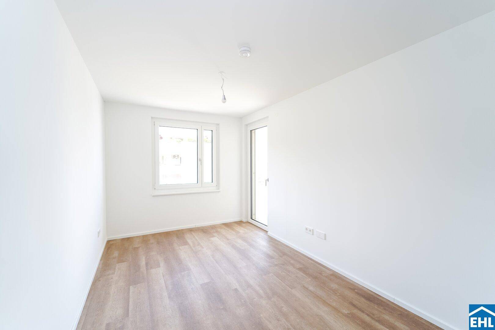 Geräumiges Schlafzimmer mit Fenster, Zugang zum Balkon und neuem Laminatboden.