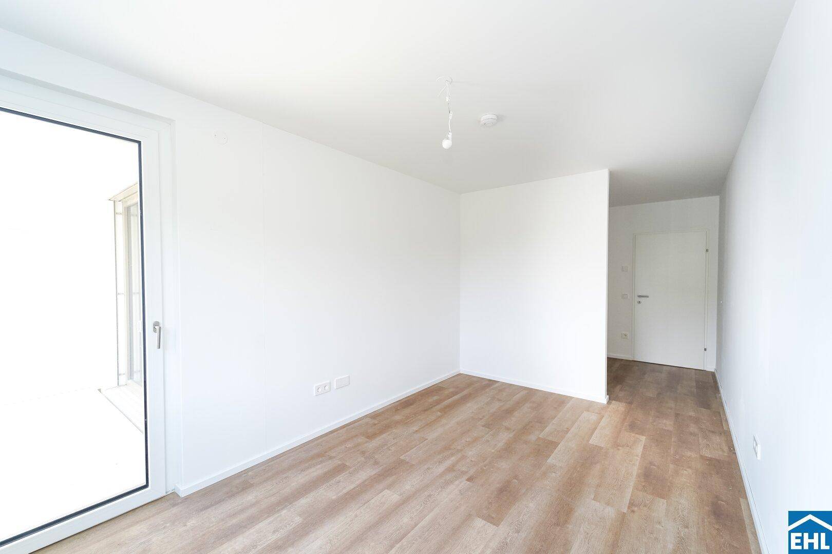 Helles Schlafzimmer mit Zugang zu einem Außenbereich und modernem Laminatboden.