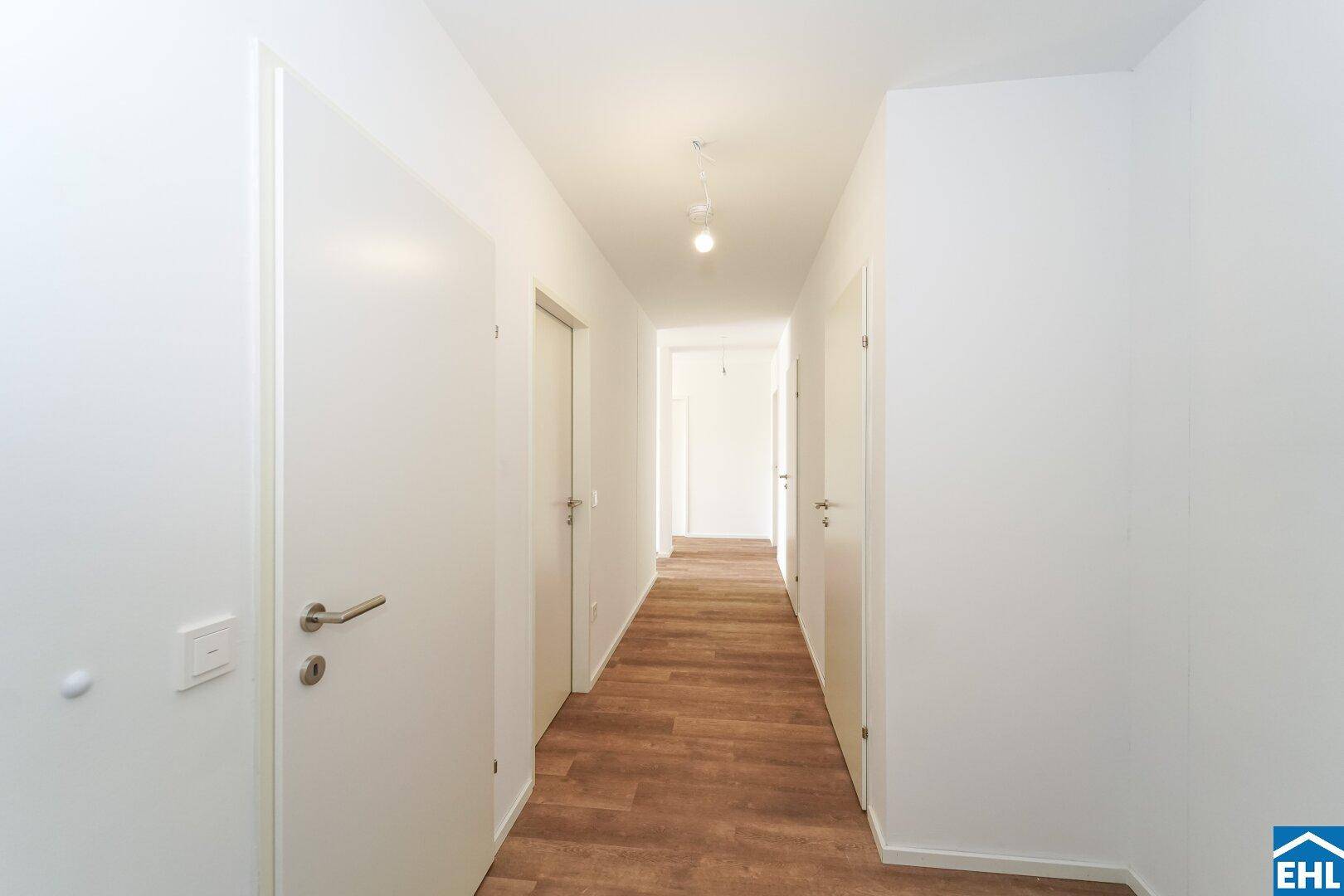 Heller Flur mit Laminatboden und mehreren weißen Türen, der die Räume verbindet.