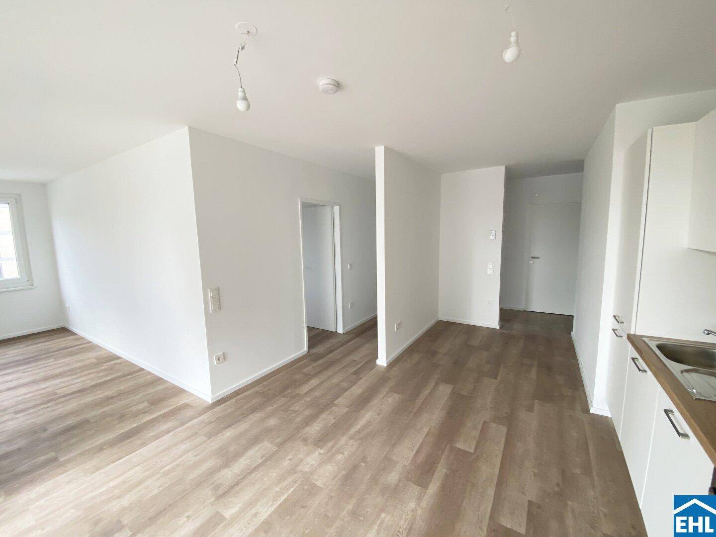 Heller, offener Wohnbereich mit neuem Laminatboden und weißen Wänden, bereit zum Einrichten.