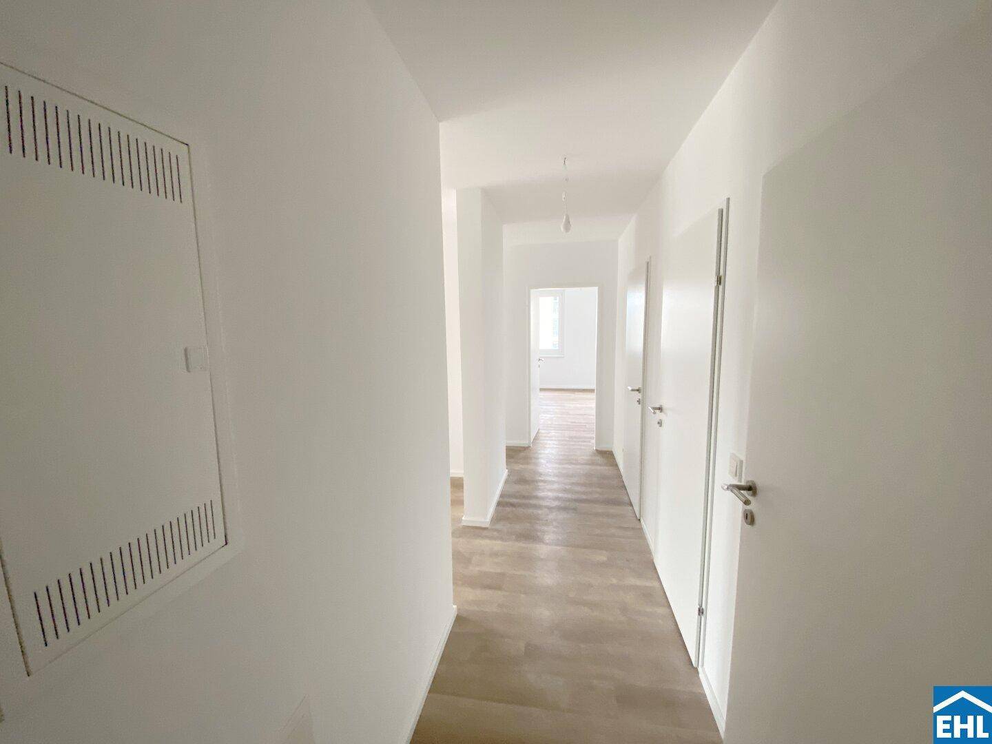 Langer, heller Flur mit Laminatboden und mehreren Türen zu den angrenzenden Räumen der Wohnung.