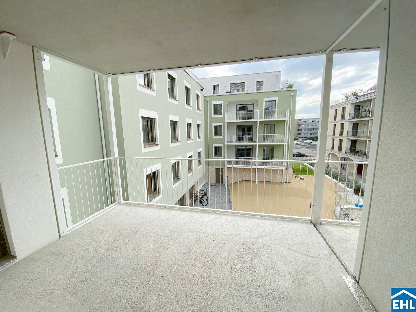 Balkon mit Blick auf den Innenhof und die umliegenden modernen Wohngebäude in einer ruhigen Lage.