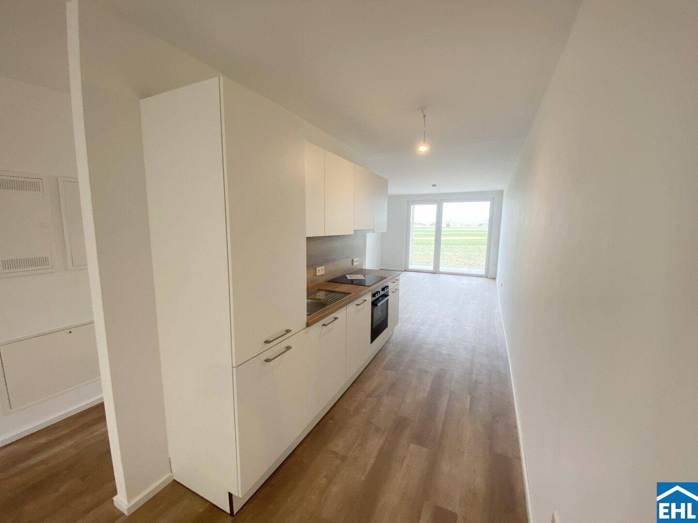 Offene Küche mit Blick in den Wohnbereich und Zugang zum sonnigen Balkon.