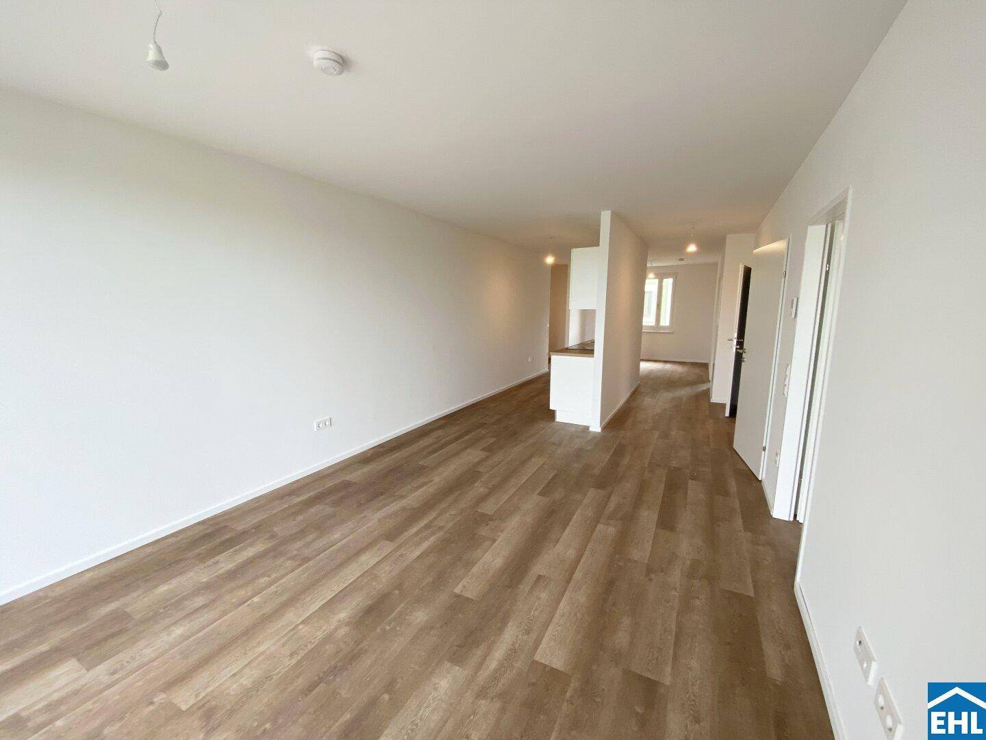 Geräumiger, heller Wohnbereich mit modernem Laminatboden und weiß gestrichenen Wänden.