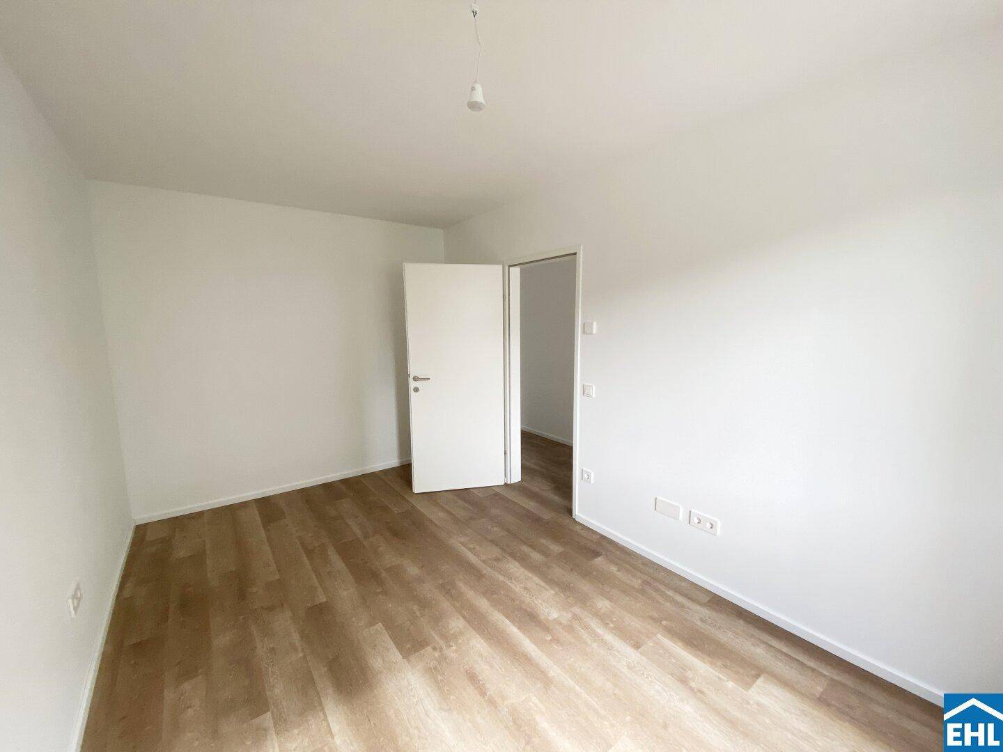Unmöbliertes Zimmer mit hellem Laminatboden und weiß gestrichenen Wänden, ideal als Schlaf- oder Arbeitszimmer.