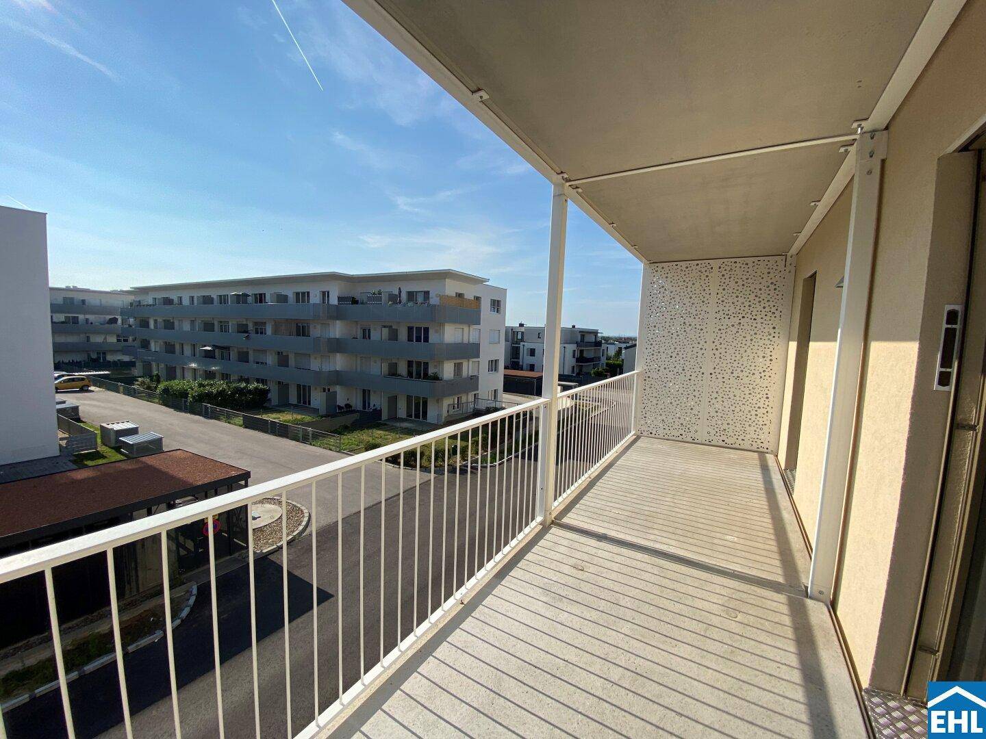 Geräumiger Balkon mit Blick auf die moderne Wohnanlage und die sonnige Umgebung.