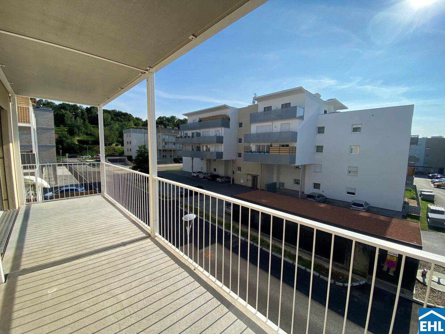 Geräumiger Balkon mit Blick auf die moderne Wohnanlage und die sonnige Umgebung.