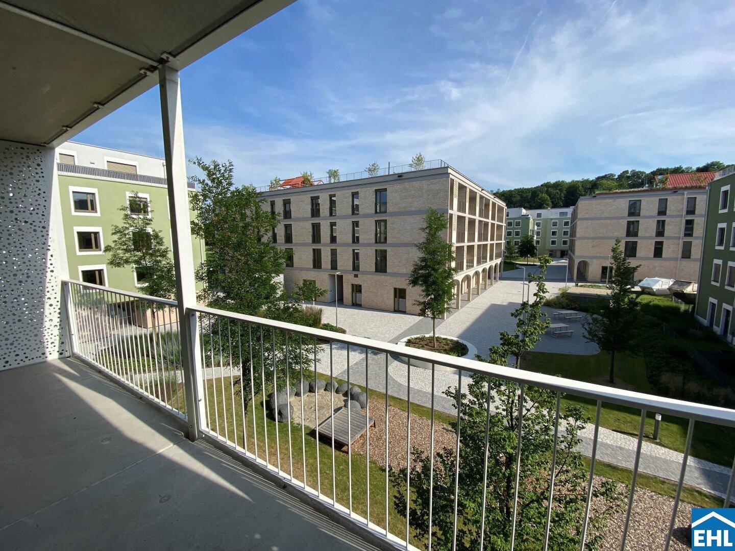 Geräumiger Balkon mit Aussicht auf die modernen Gebäude und den gepflegten Innenhof.