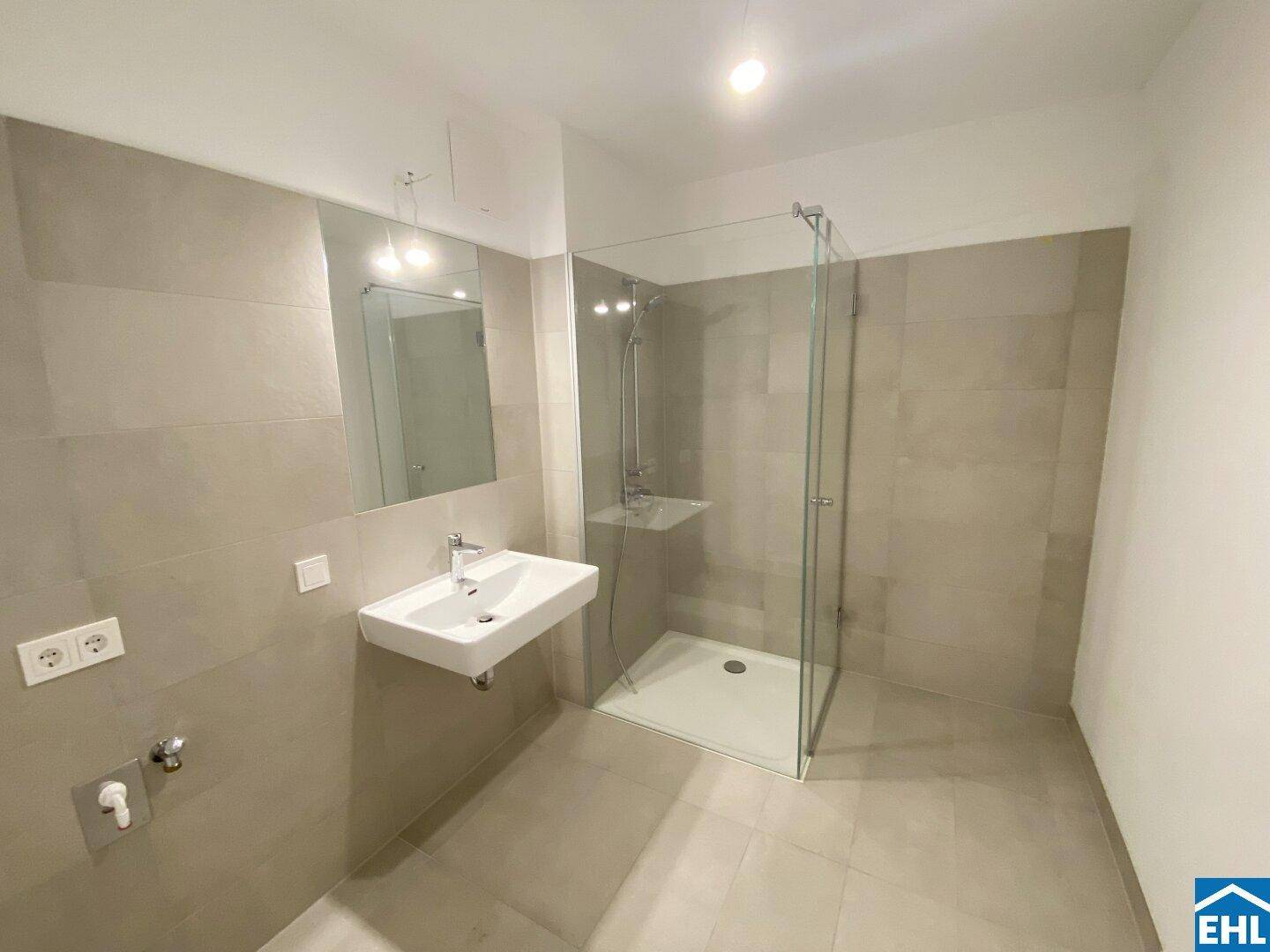 Modernes Badezimmer mit grauen Fliesen, Einzelwaschbecken und einer begehbaren Dusche.