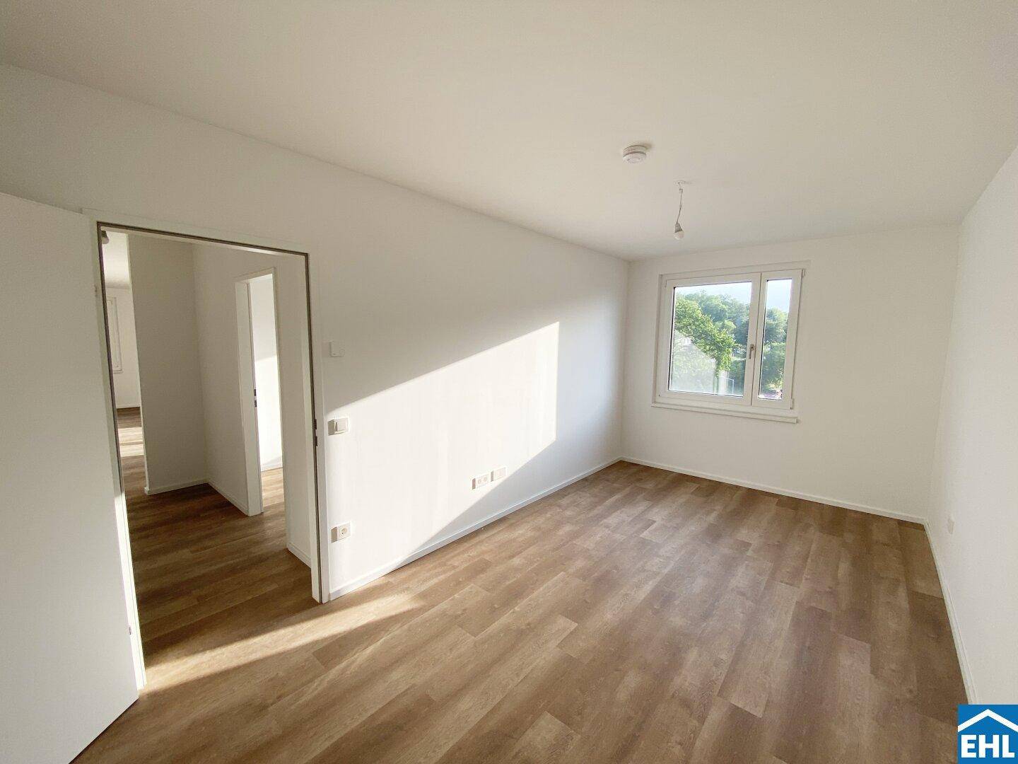 Freundliches Zimmer mit Laminatboden und einem Fenster, das viel Tageslicht hereinlässt.