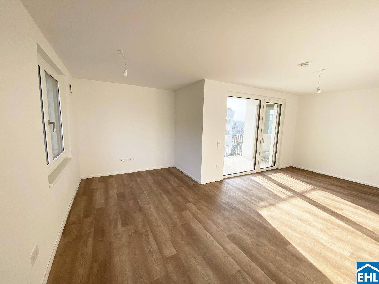 Heller, leerer Raum mit Holzboden und Schiebetür zum Balkon, ideal als Wohn- oder Schlafzimmer.