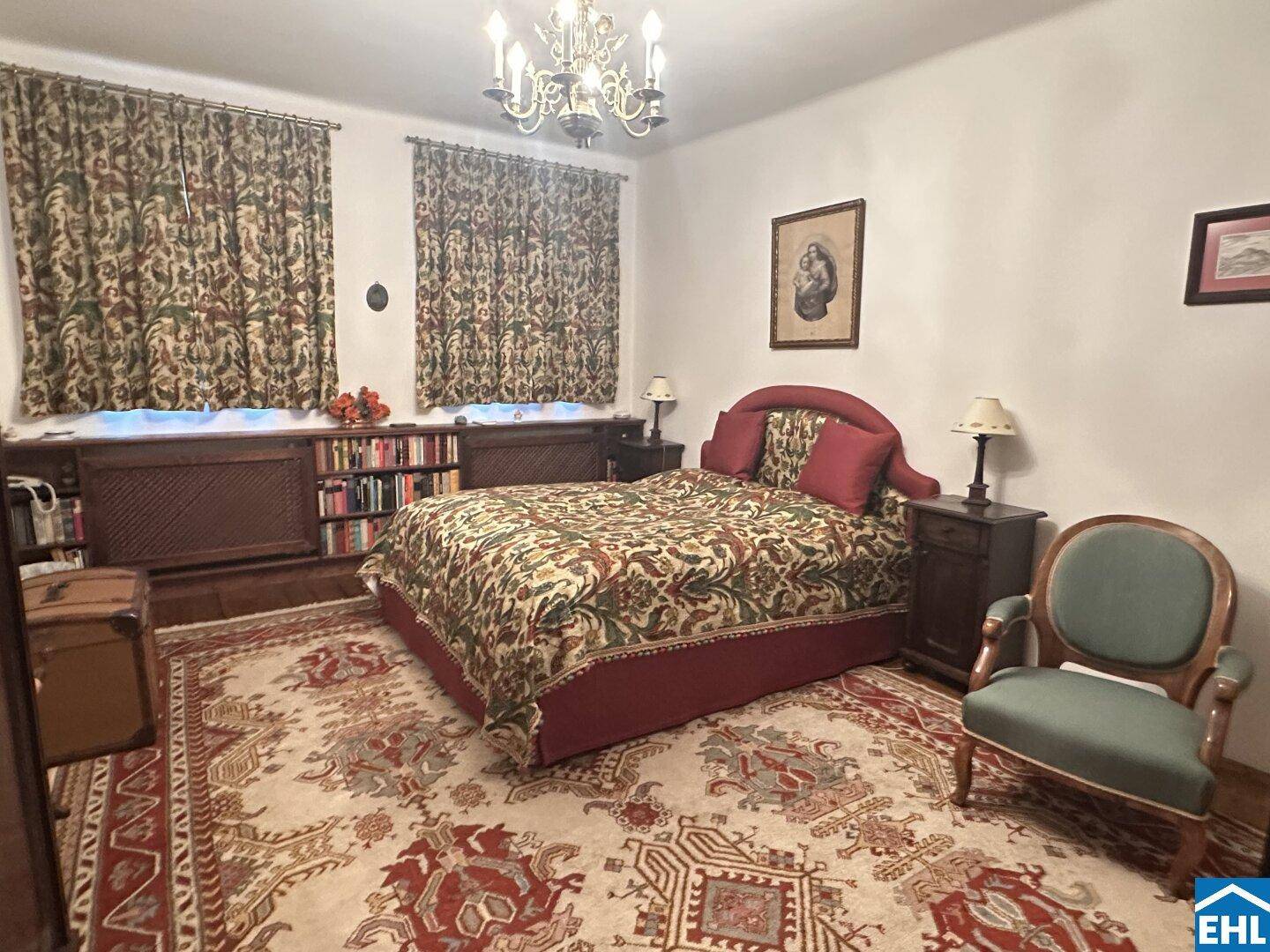Helles Schlafzimmer mit traditionellem Dekor, Holzbalkendecke und großem Bett mit gemustertem Bezug.