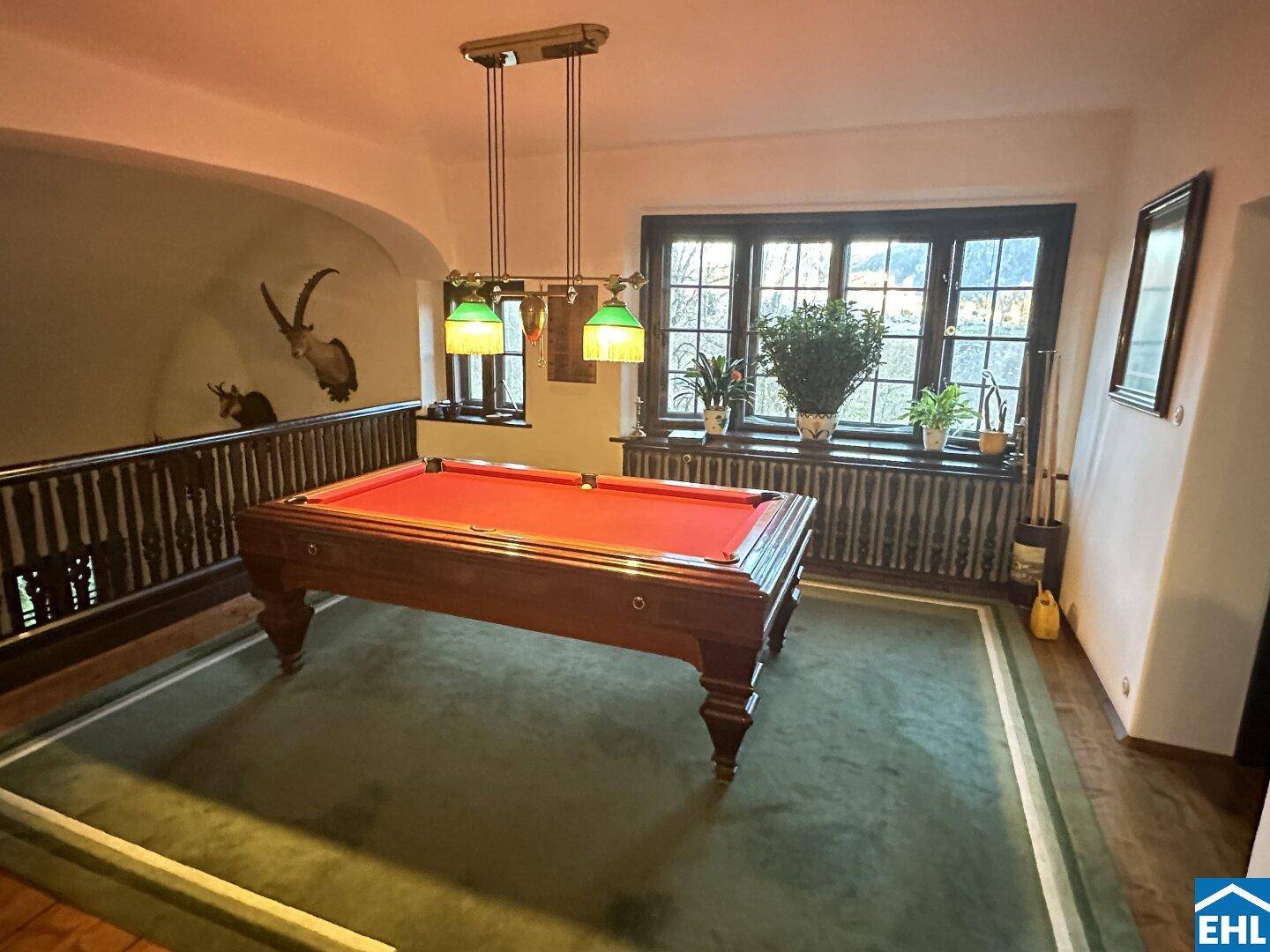 Spielzimmer mit Billardtisch, großen Fenstern und Blick auf die umliegende Landschaft.