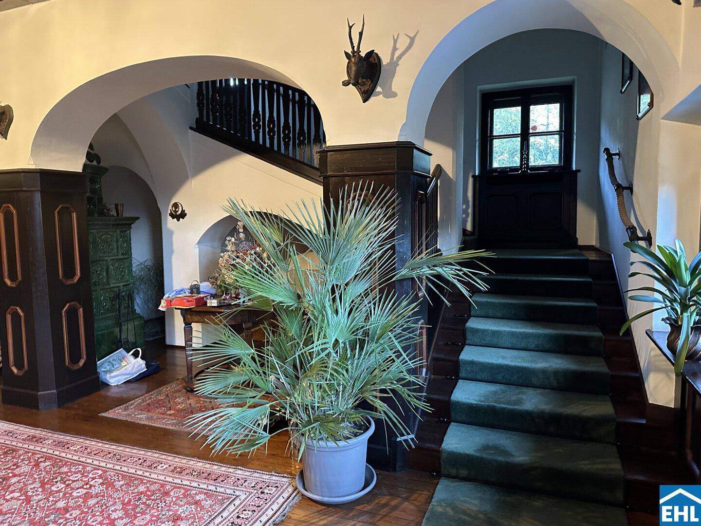Großzügiger Eingangsbereich mit geschwungener Treppe, Holzelementen und traditioneller Dekoration.