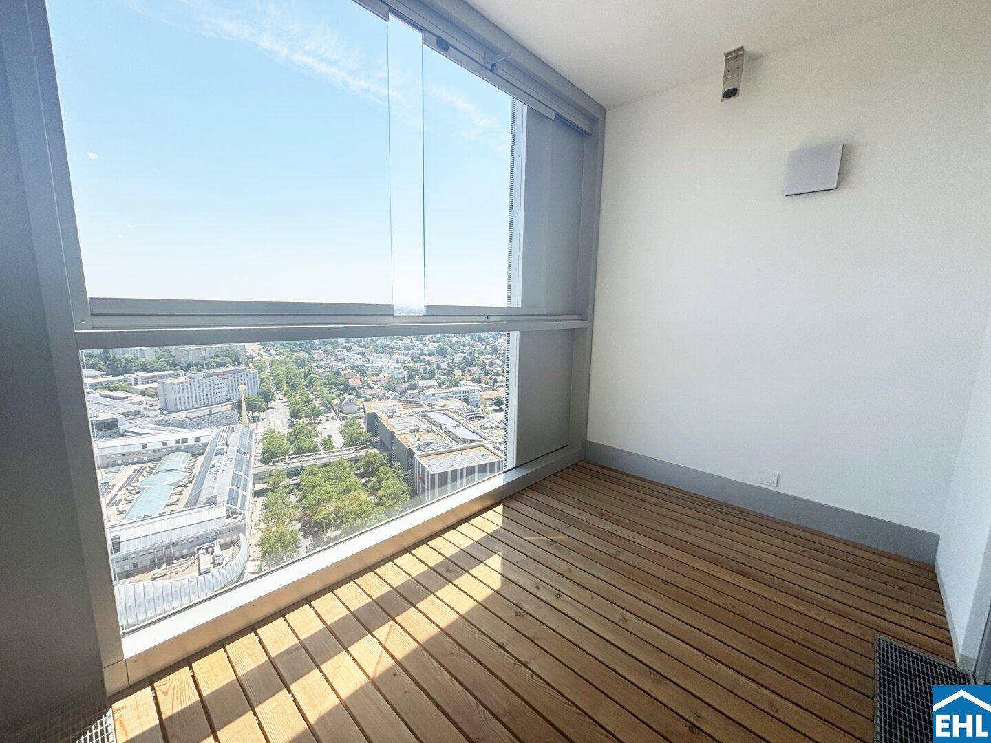 Verglaste Loggia mit Holzboden und weitem Blick über die Stadt und die umliegende Landschaft.