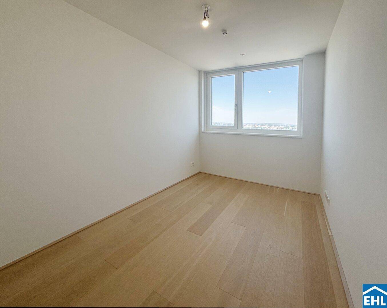 Ruhiges Schlafzimmer mit Holzboden und Fenster, das einen weiten Blick über die Umgebung bietet.
