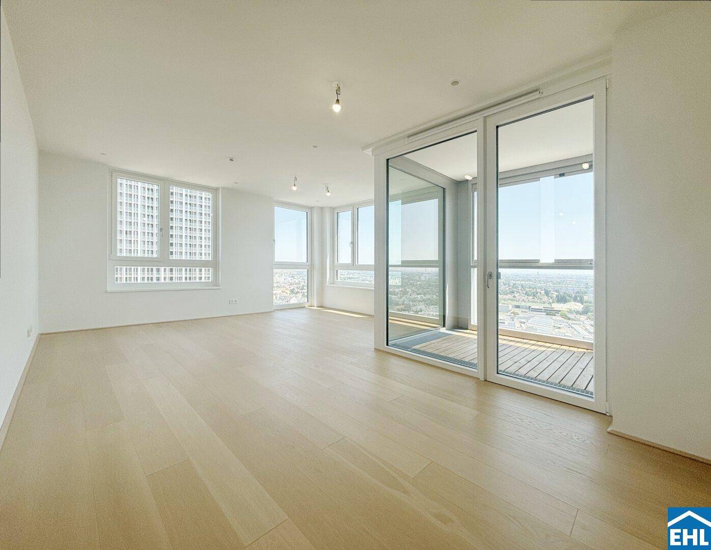 Geräumiges Wohnzimmer mit Holzboden, vielen Fenstern und Panoramablick über die Stadt.