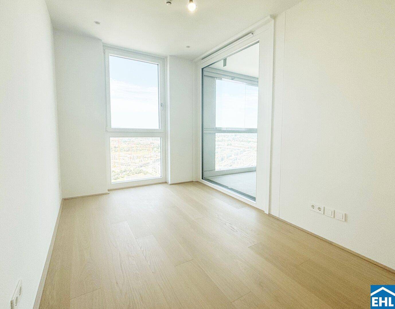 Helles Schlafzimmer mit Holzboden und großen Fenstern, die einen weiten Ausblick bieten.