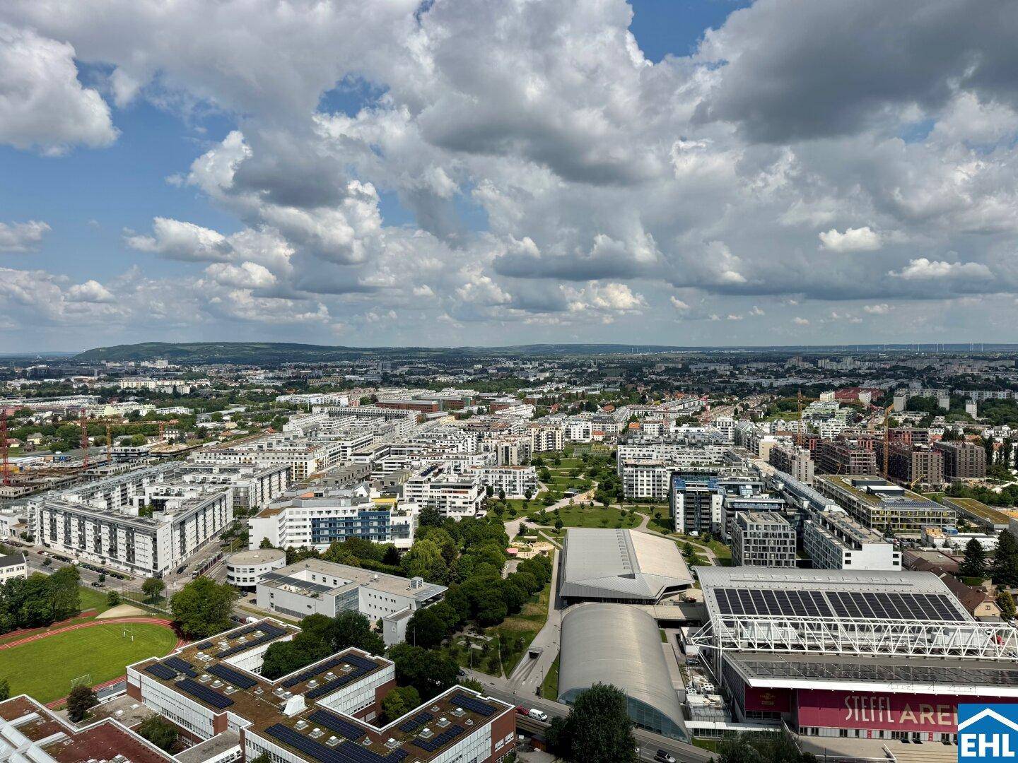 Weitläufiger Panoramablick über die Stadt und die umliegende Landschaft unter einem bewölkten Himmel.
