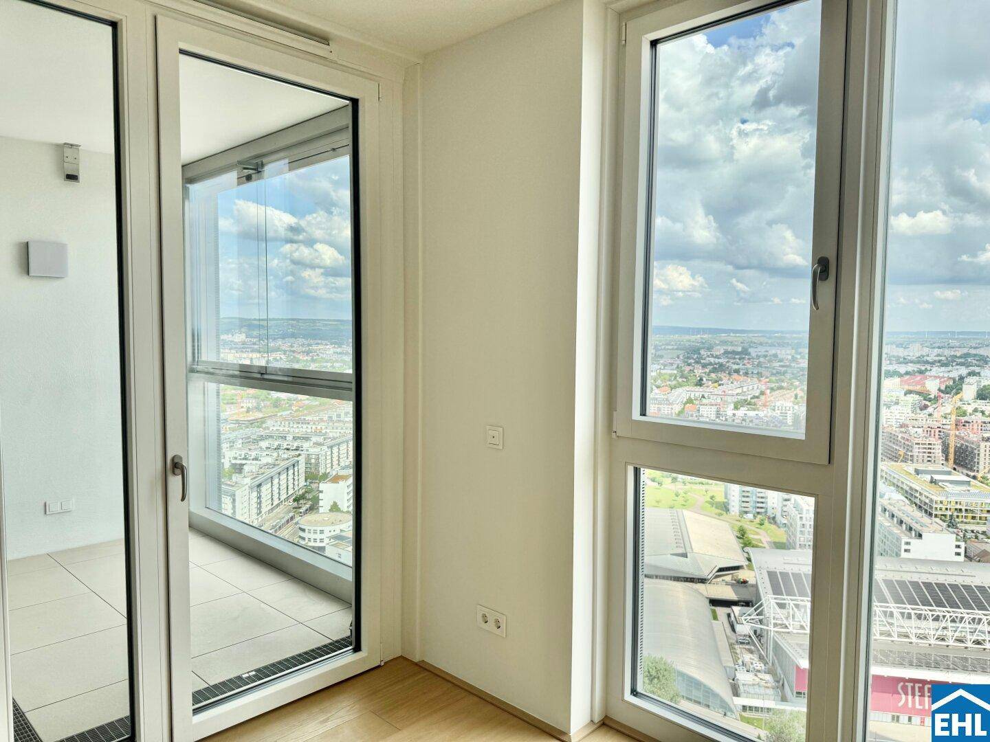 Große Fensterfront mit Zugang zu einem Balkon, der einen beeindruckenden Panoramablick auf die Stadt bietet.
